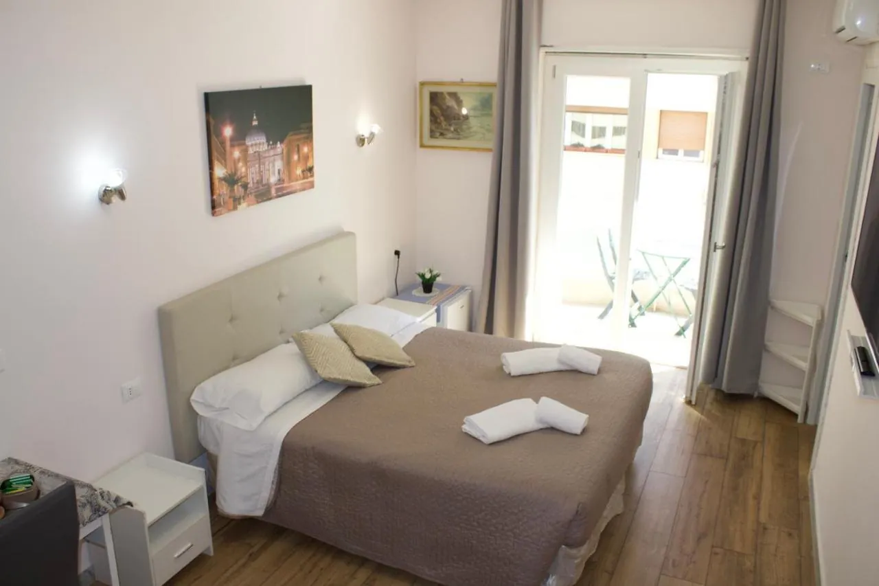 Letto matrimoniale con testiera chiara e porta-finestra sul balcone