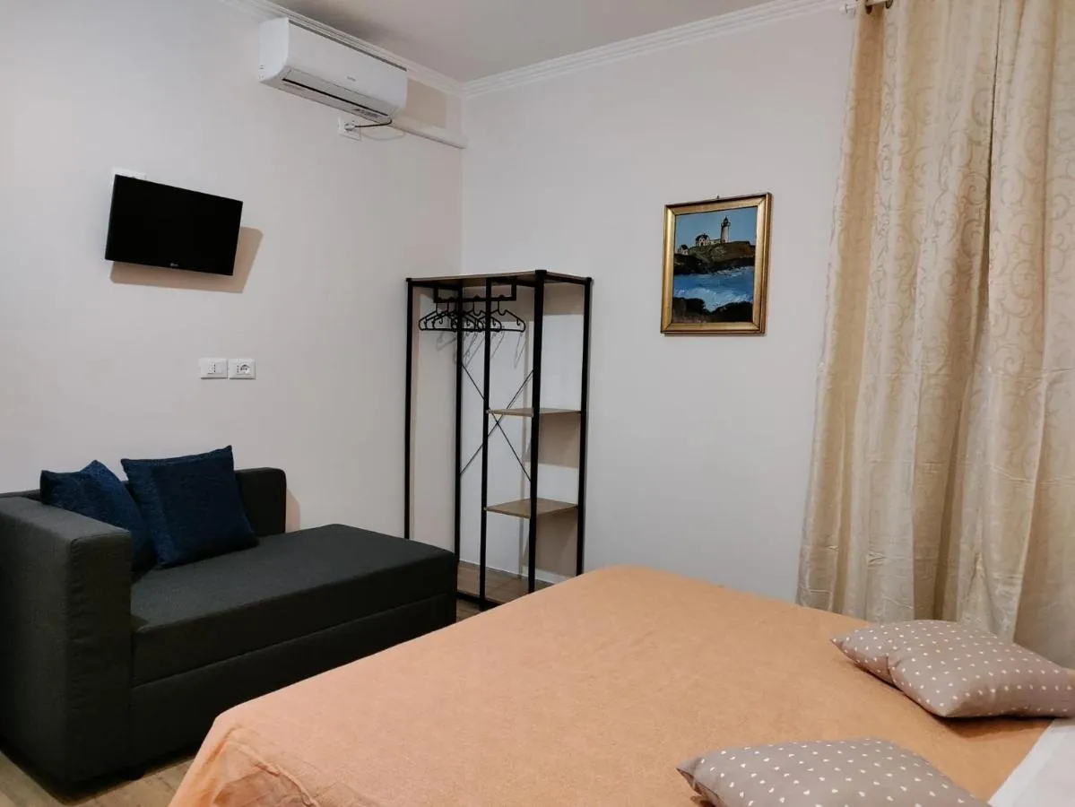 Camera con letto matrimoniale dal copriletto arancione e divano letto scuro con cuscini