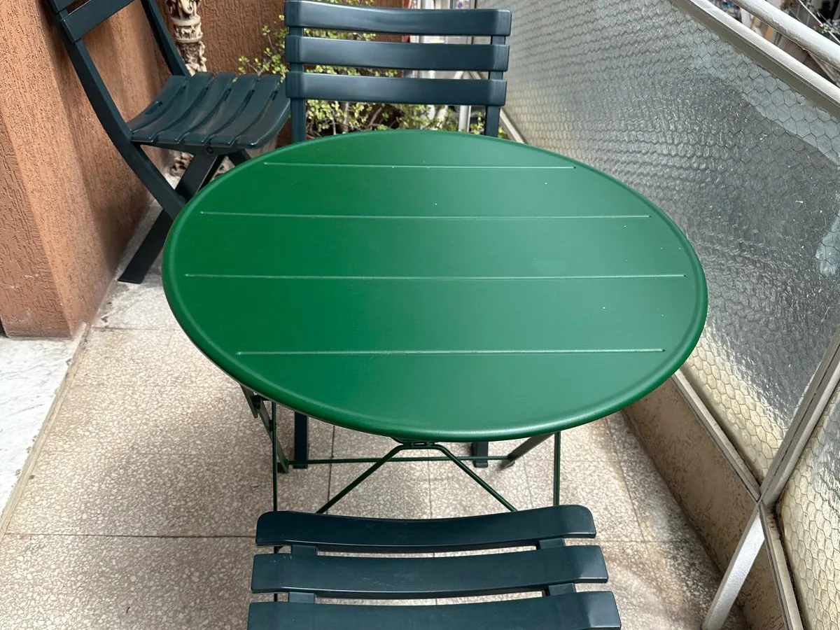 Il balcone con il tavolo verde e le sedie pieghevoli
