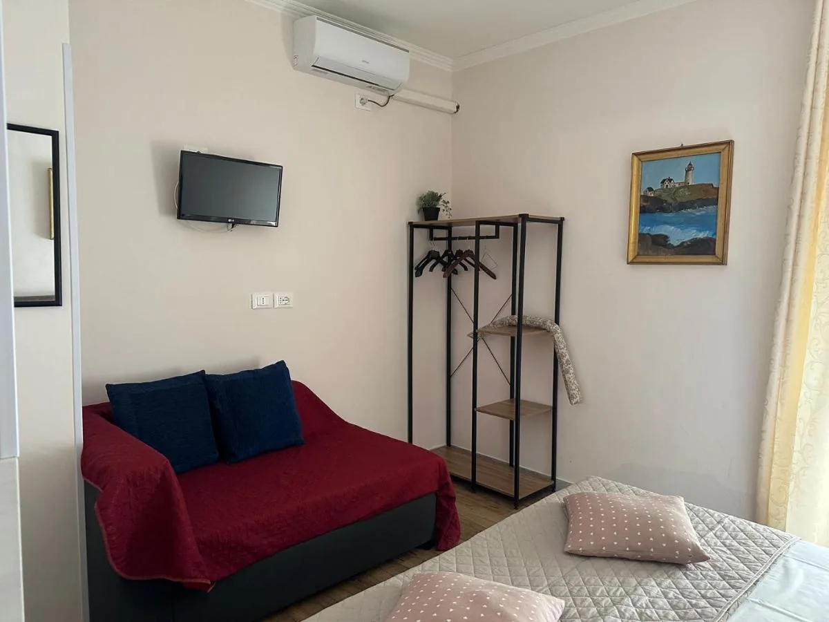 Il divano letto con la coperta rossa e la TV a parete