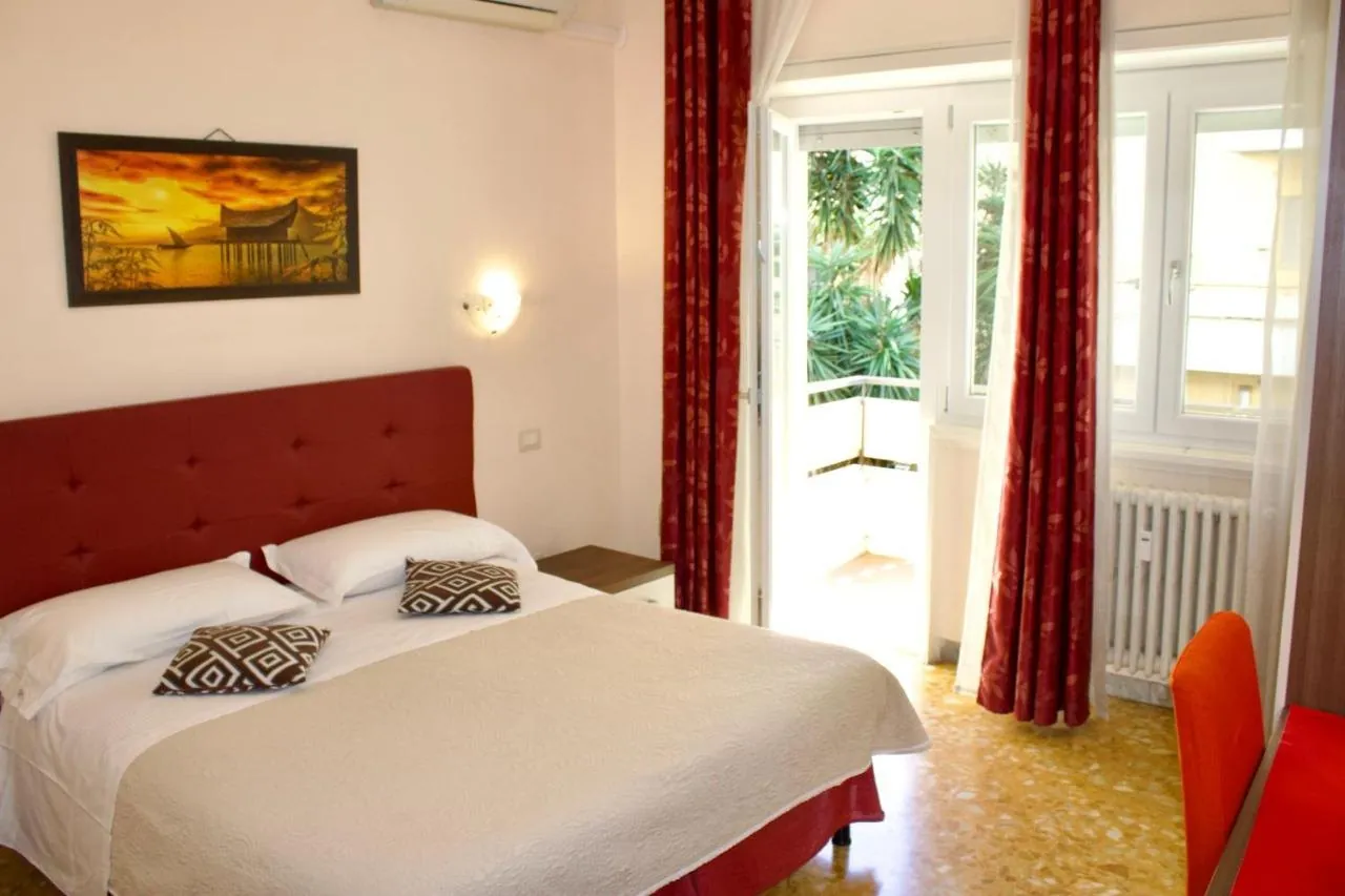 Letto matrimoniale e porta-finestra sul balcone con le palme