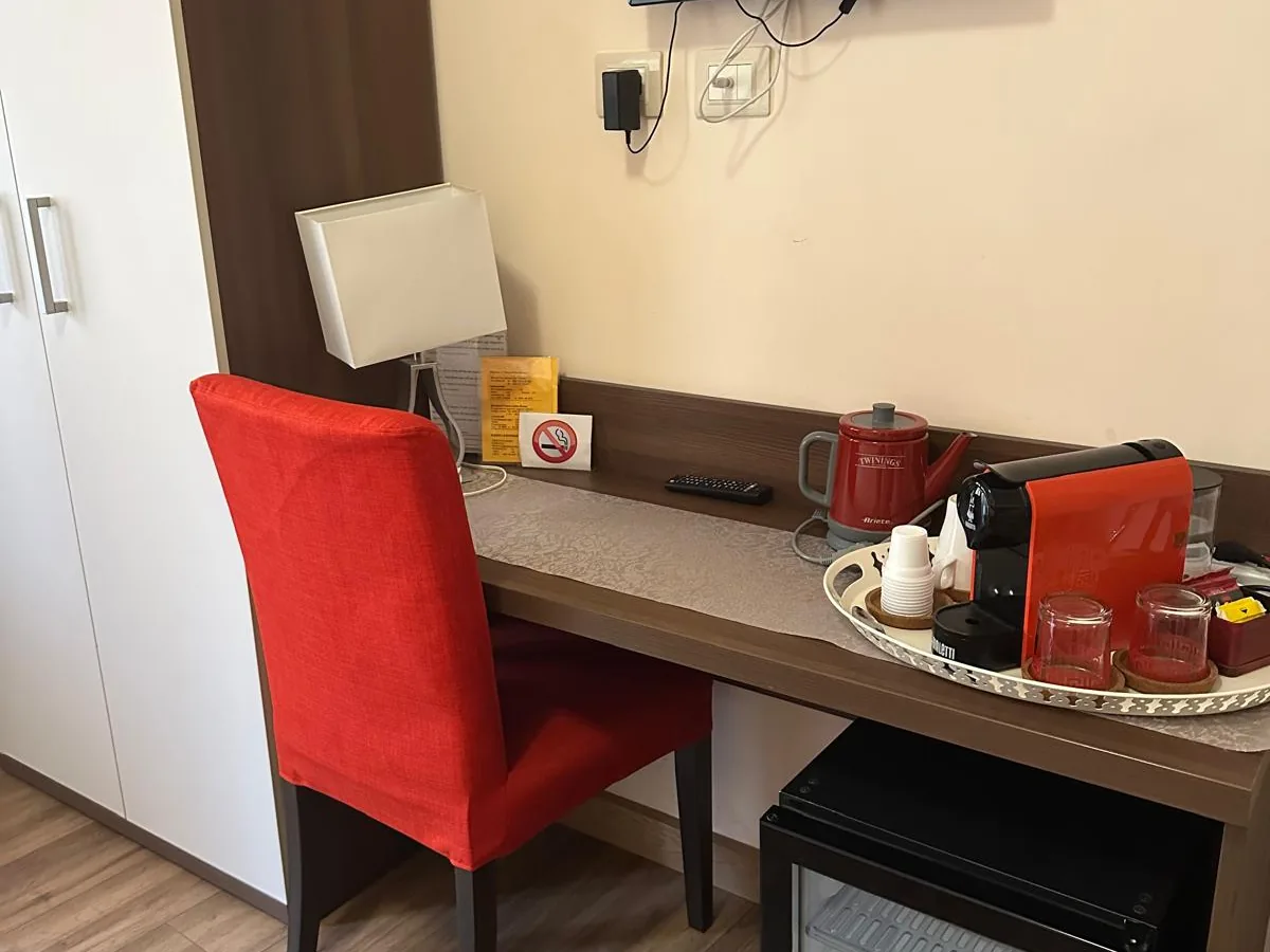 La scrivania con la macchina del caffè a cialde, il bollitore e, sotto, il minifrigo