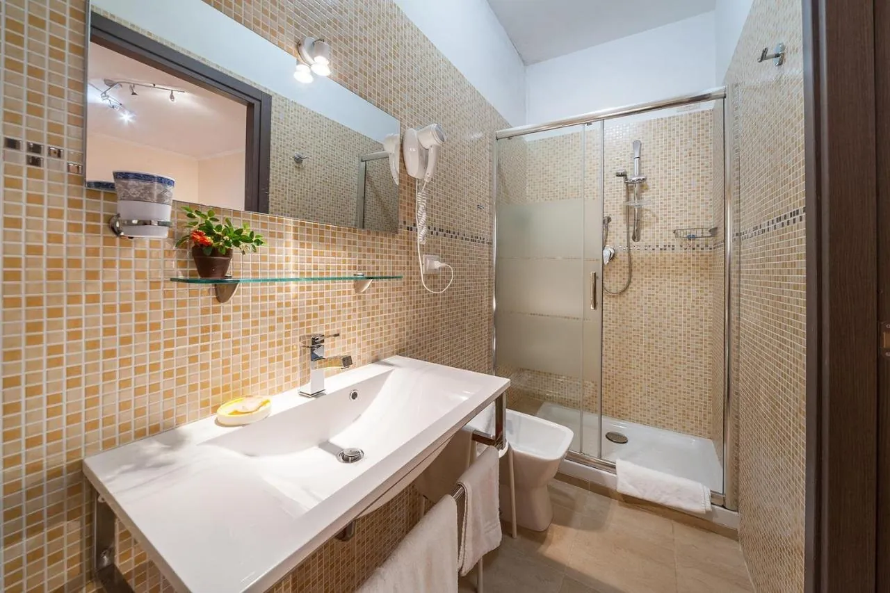 Bagno privato con lavabo ampio e doccia, piastrelle a mosaico