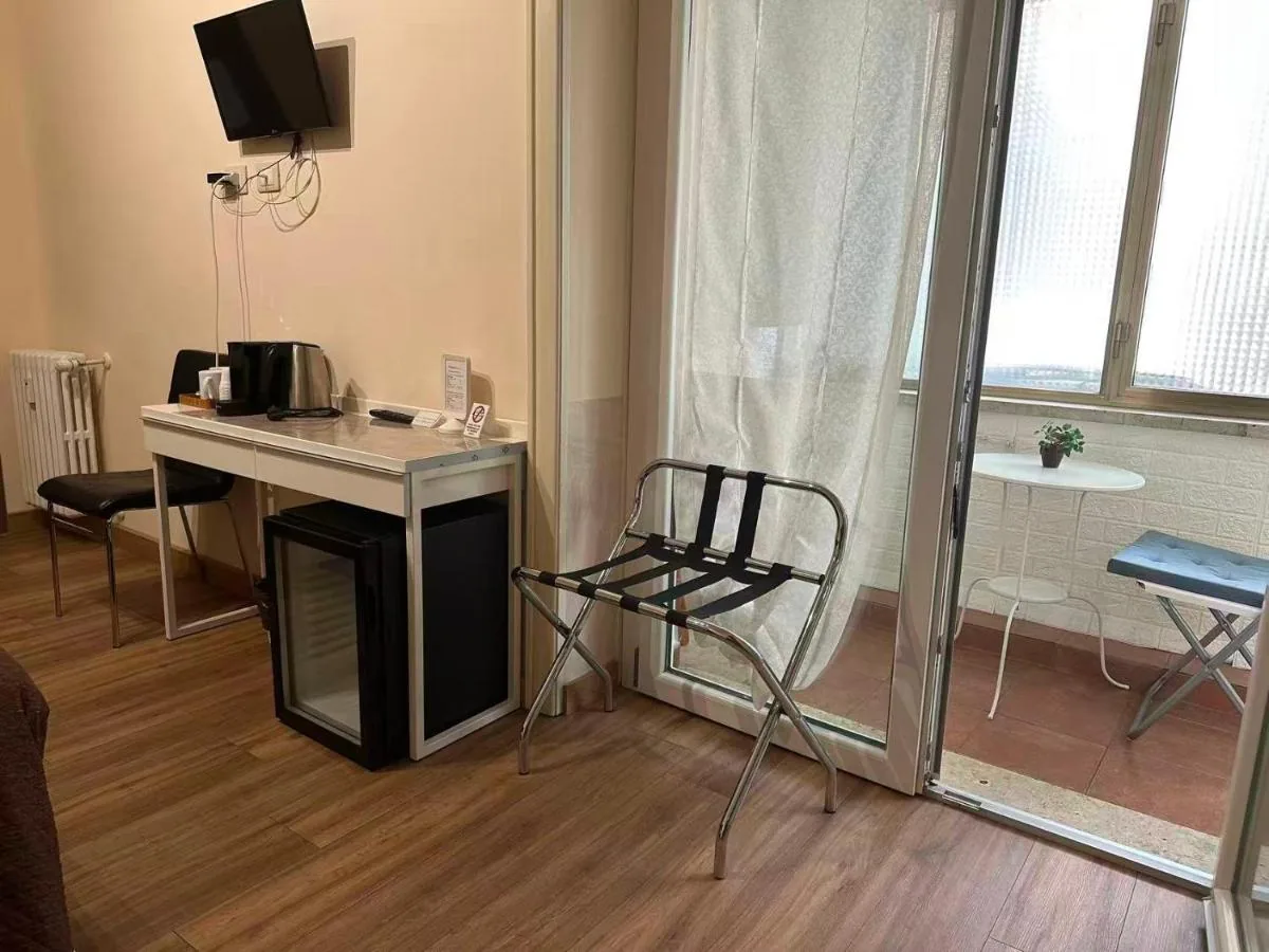 La scrivania con bollitore e minifrigo, e la porta-finestra sul balcone con il tavolino
