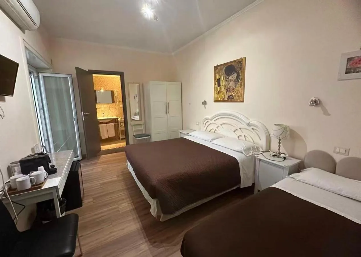 La camera tripla vista dalla porta, con i due letti, la scrivania e il bagno