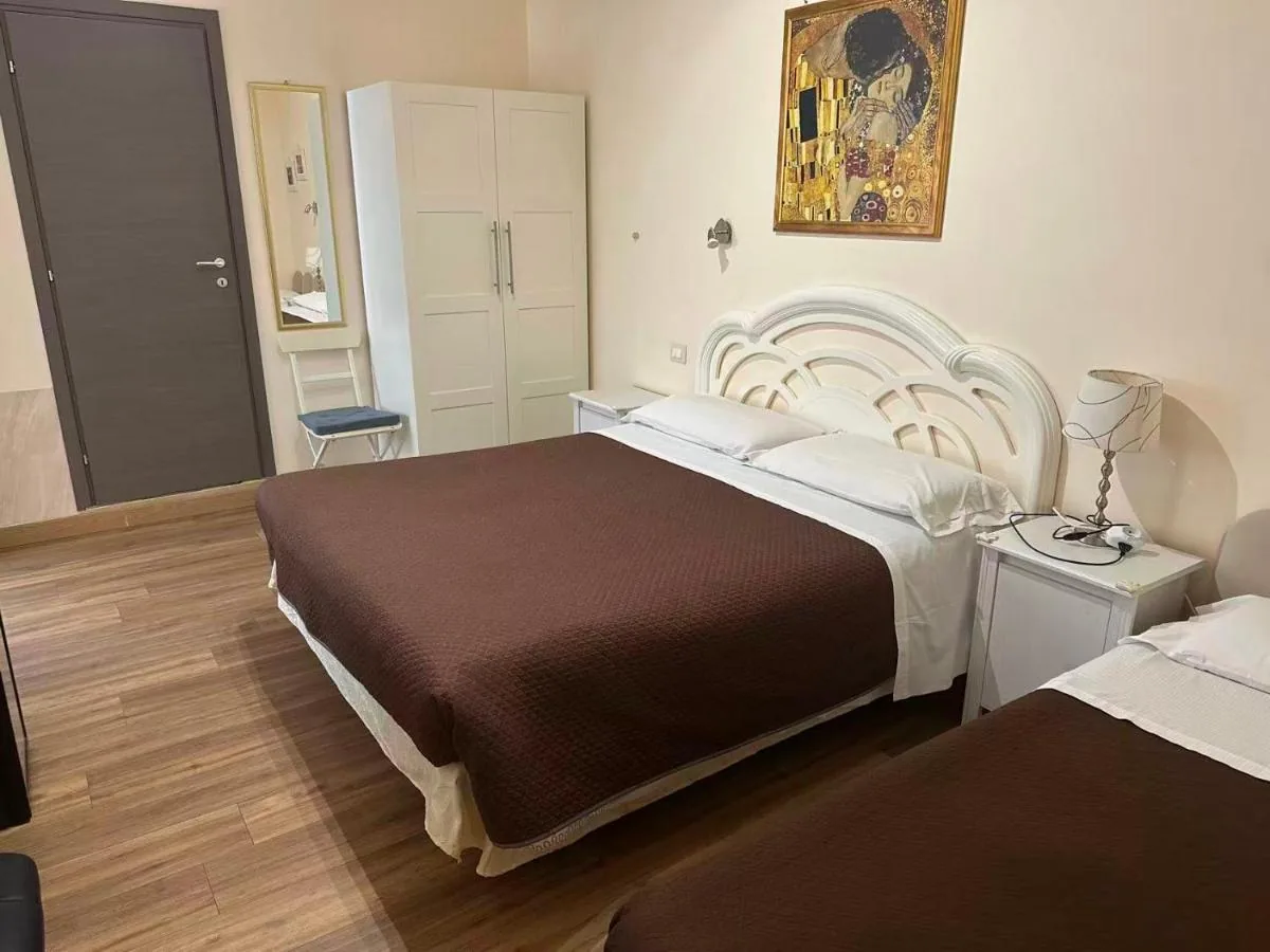 Camera tripla con letto matrimoniale e letto singolo, coperte marroni e armadio bianco